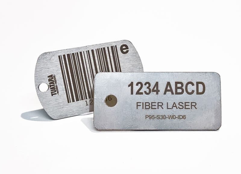 Two stainless steel barcode and identification tags engraved with fiber laser technology, featuring alphanumeric codes and a barcode design.